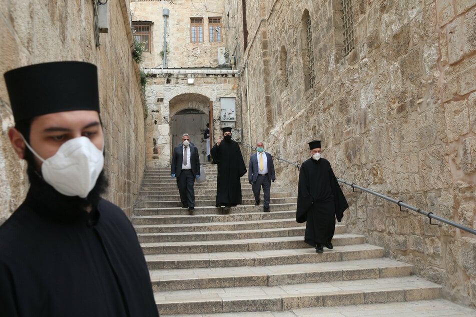Orthodoxe christliche Geistliche mit Mundschutz gehen am orthodoxen Karfreitag in der Nähe der Grabeskirche durch die Jerusalemer Altstadt. (Archivbild)