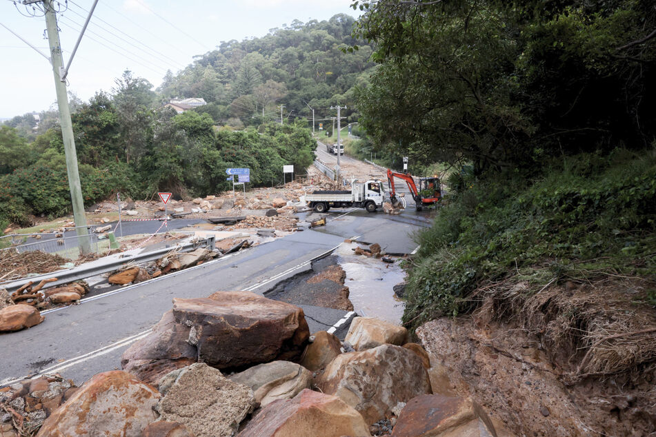 Nach einem Erdrutsch machten sich Arbeiter daran, herabgestürzte Felsbrocken von einer Straße zu schaffen.