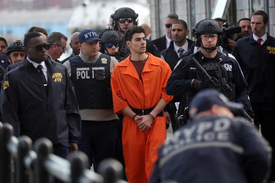 Luigi Mangione (c.), suspect in the killing of UnitedHealthcare CEO Brian Thompson in New York City, arrives at a heliport with members of the NYPD on December 19, 2024 in New York City.