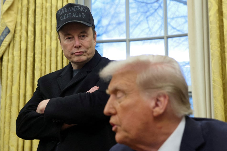 Elon Musk stands next to President Donald Trump in the Oval Office of the White House.