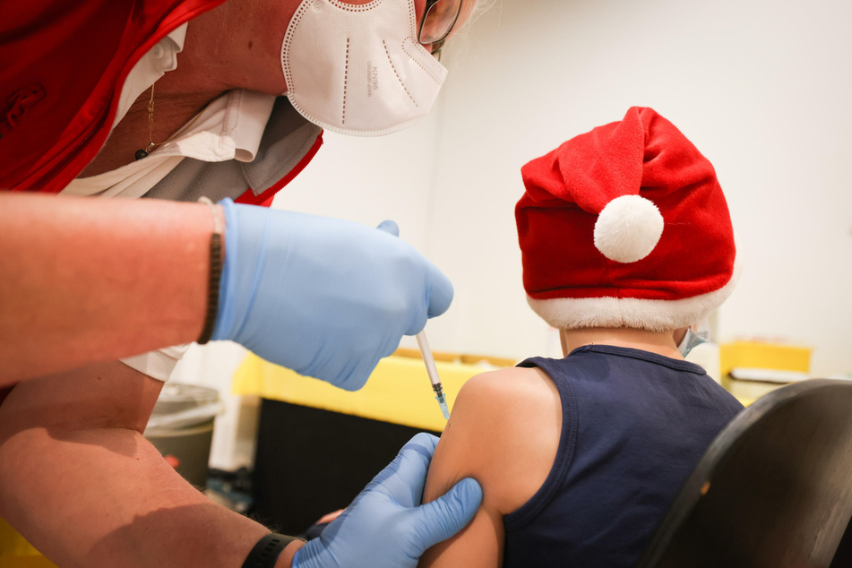 Ein Junge mit Weihnachtsmütze wird bei einer Impfaktion im Einkaufszentrum mit dem Impfstoff von Biontech/Pfizer geimpft.