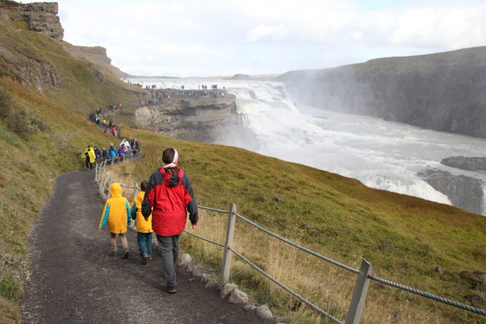 Island, Geysir: Touristen wandern zum isländischen Wasserfall Gullfoss.