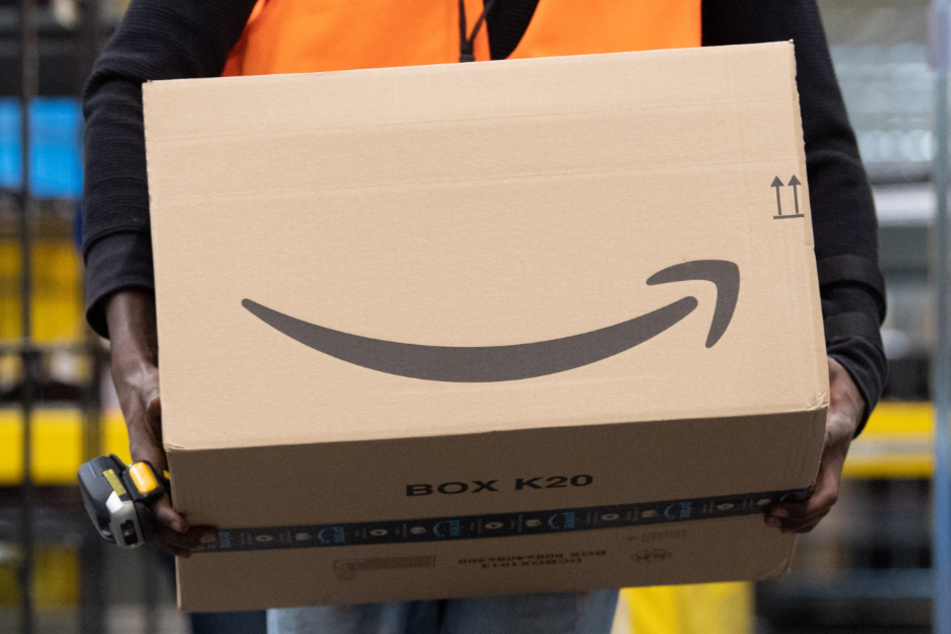Ein Sortiermitarbeiter von Amazon trägt in einem Verteilzentrum ein Paket. Verbraucherschützer sehen die zunehmende Marktmacht großer Online-Plattformen wie Amazon mit Sorge.