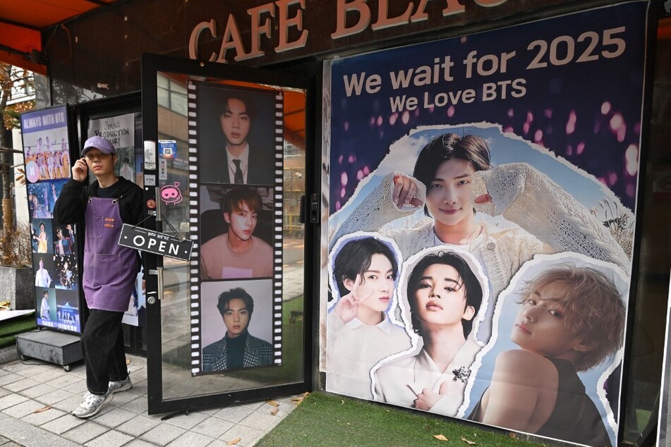 A poster reading "We wait for 2025" and showing images of members of BTS hangs in front of a cafe in Seoul, South Korea, on December 12, 2023.