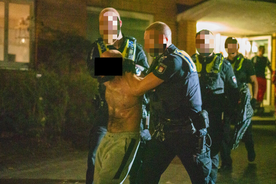 Polizisten führen den halbnackten Mann ab.