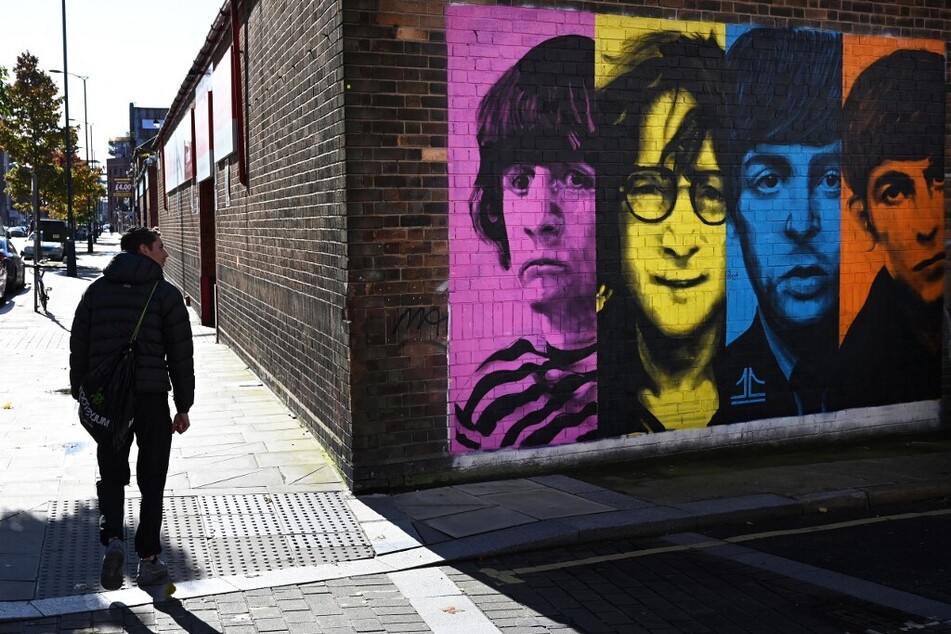 Pedestrians pass a mural depicting members of British rock band The Beatles on the side of a building in Liverpool, northwest England.