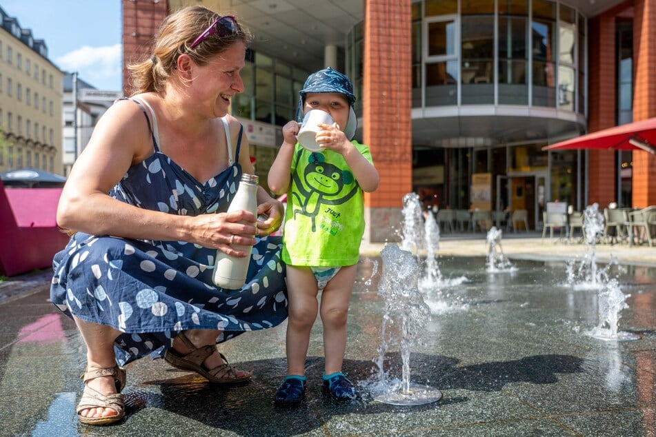 Anne Zehrt (37) und ihr einjähriger Sohn kühlen sich am Brunnen auf dem Jakobikirchplatz ab.