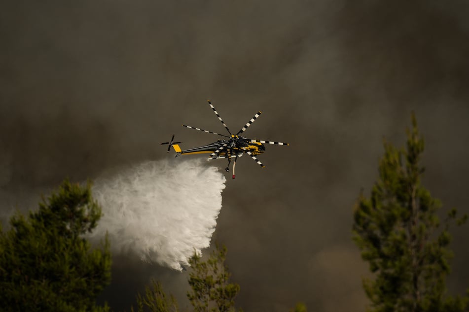 A firefighting helicopter drops water over a cloud of smoke from a wildfire in the area of Porto Germeno on Sunday.
