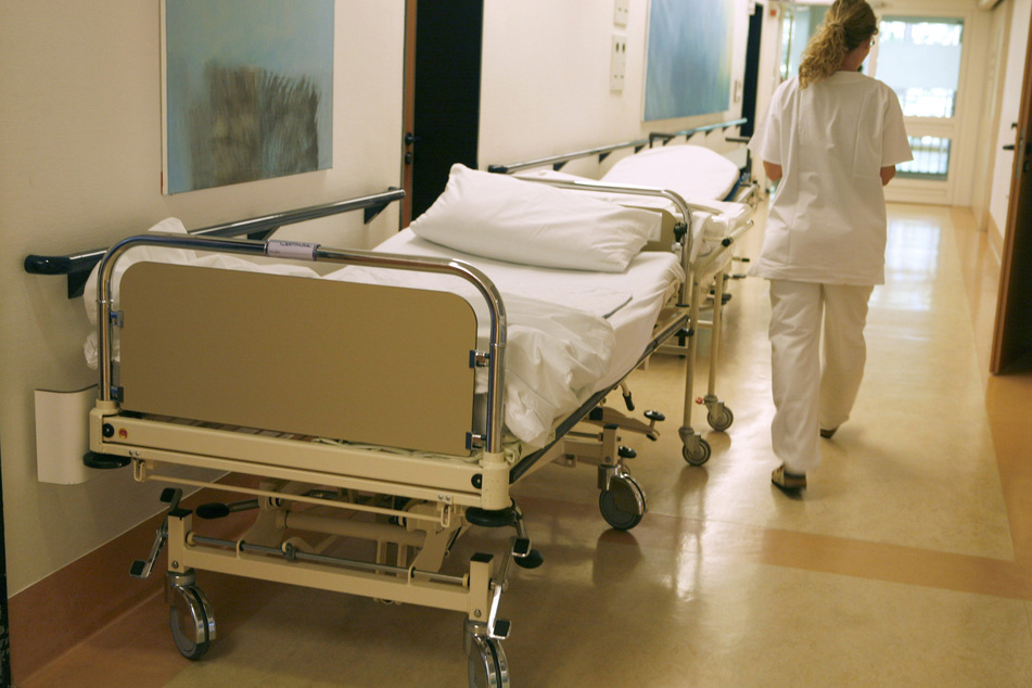 Eine Krankenschwester eilt auf einem Flur an einem leeren Bett vorbei. (Symbolfoto)