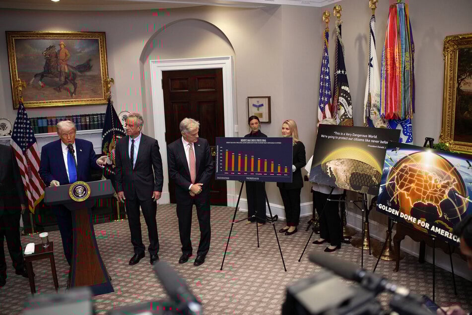 President Donald Trump (L) – joined by Human Services Secretary Robert F. Kennedy Jr. (C), and Administrator for the Centers for Medicare & Medicaid Services (CMS) Mehmet Oz – points to posters on the Golden Dome missile defense system during a press conference in the Roosevelt Room of the White House on May 12, 2025, in Washington, DC.