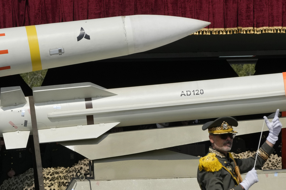 Raketen werden auf einem Lastwagen transportiert, während ein iranischer Militärkapellmeister die Musikkapelle während der Parade zum Tag der Armee auf einem Militärstützpunkt im Norden Teherans dirigiert. (Archivbild)