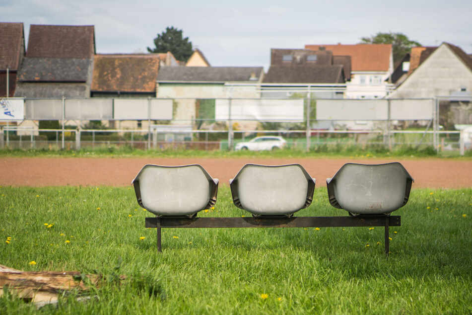 Verlassen stehen neben einem Dorfsportplatz drei Sitzplätze am Spielfeldrand. Die Amateurfußball-Saison in Bayern wurde endgültig abgebrochen.