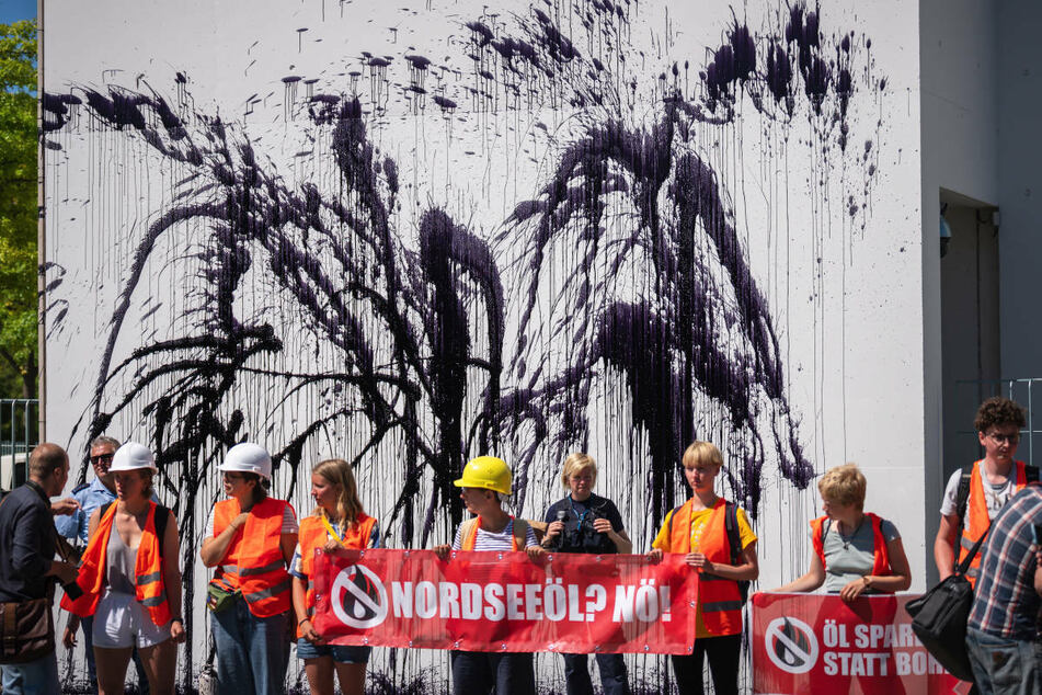 Mitglieder der Klimaschutzinitiative "Letzte Generation" stehen vor der beschmierten Wand am Kanzleramt.
