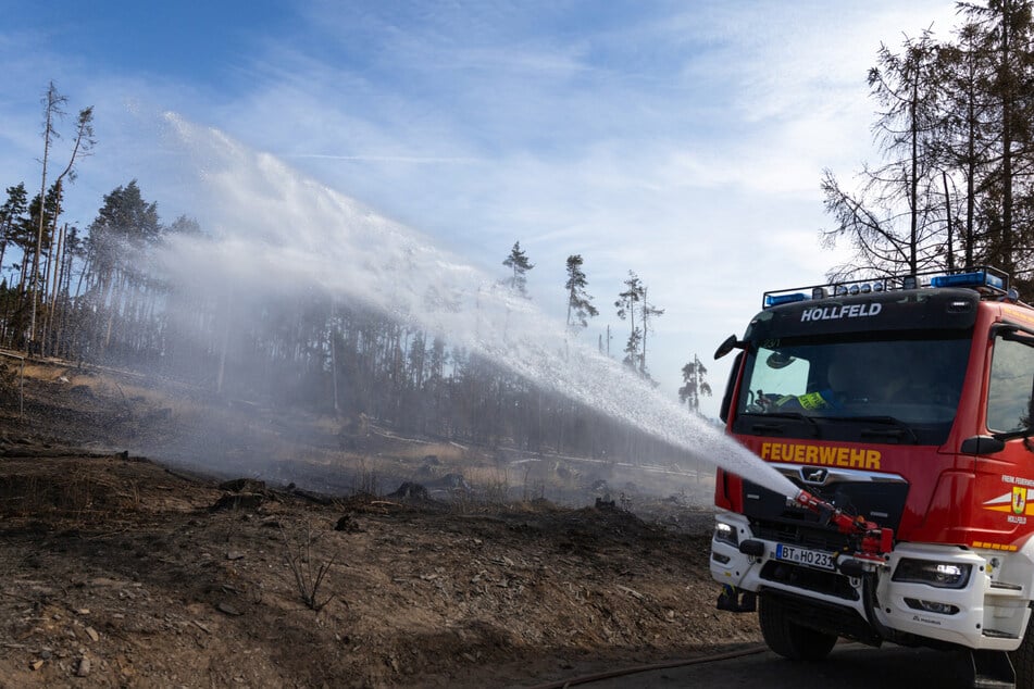 Ein Feuerwehrfahrzeug aus Bayreuth spritzt Löschwasser auf versteckte Glutnester beim Waldbrand auf der Saalfelder Höhe. (Archivbild)