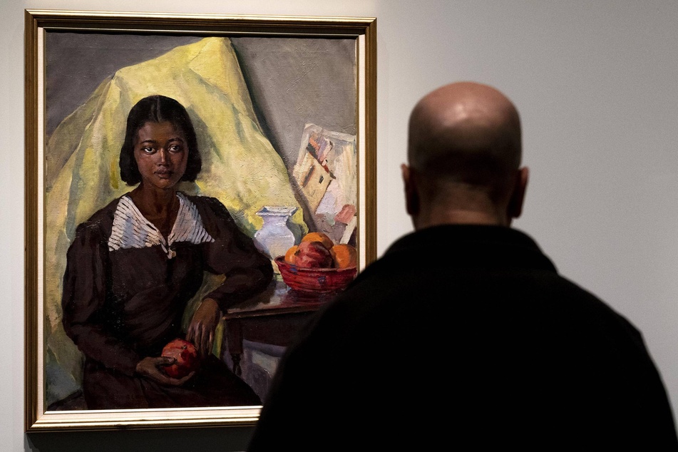 A visitor looks at a painting entitled Girl With Pomegranate by Laura Wheeler Waring on view at the Harlem Renaissance Exhibition at The Metropolitan Museum.