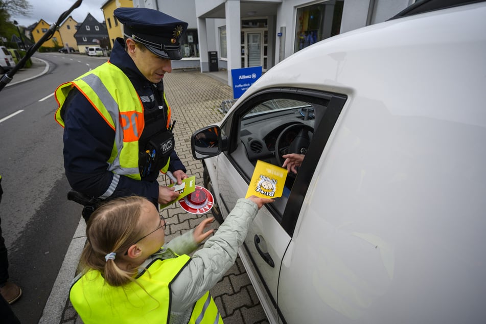 So geht's nicht! Ella (9) und Polizeiobermeister Tobias Heinicke (40) geben einem Autofahrer eine gelbe Karte.