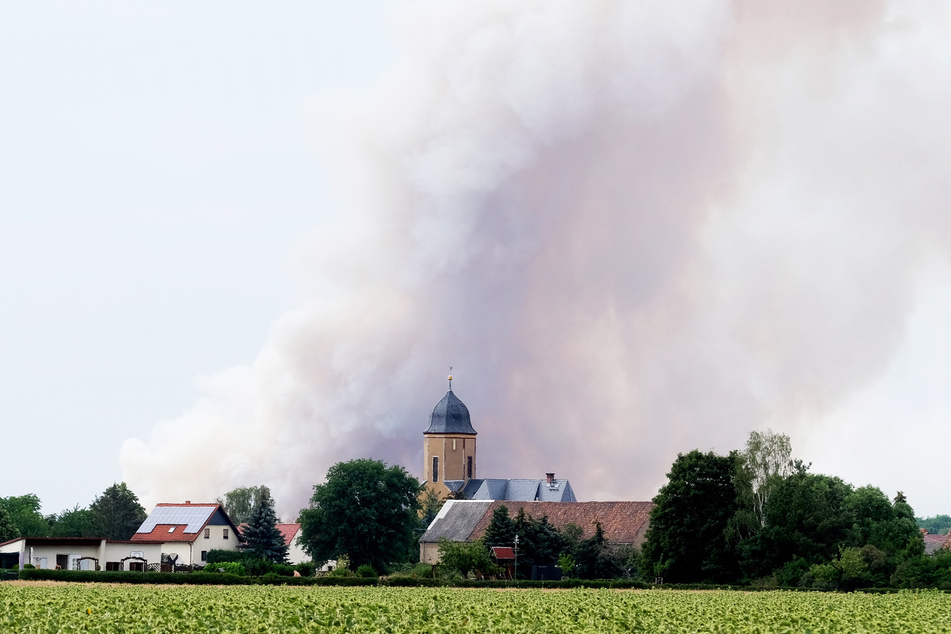 Rauch des Brandes in der Gohrischheide steigt über dem Dorf Lichtensee (Landkreis Meißen) auf.
