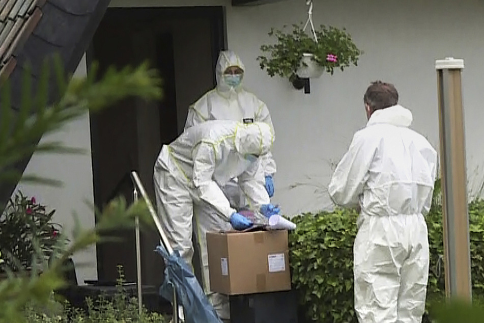 Mitarbeiter der Spurensicherung stehen vor dem Haus des getöteten Ehepaares.