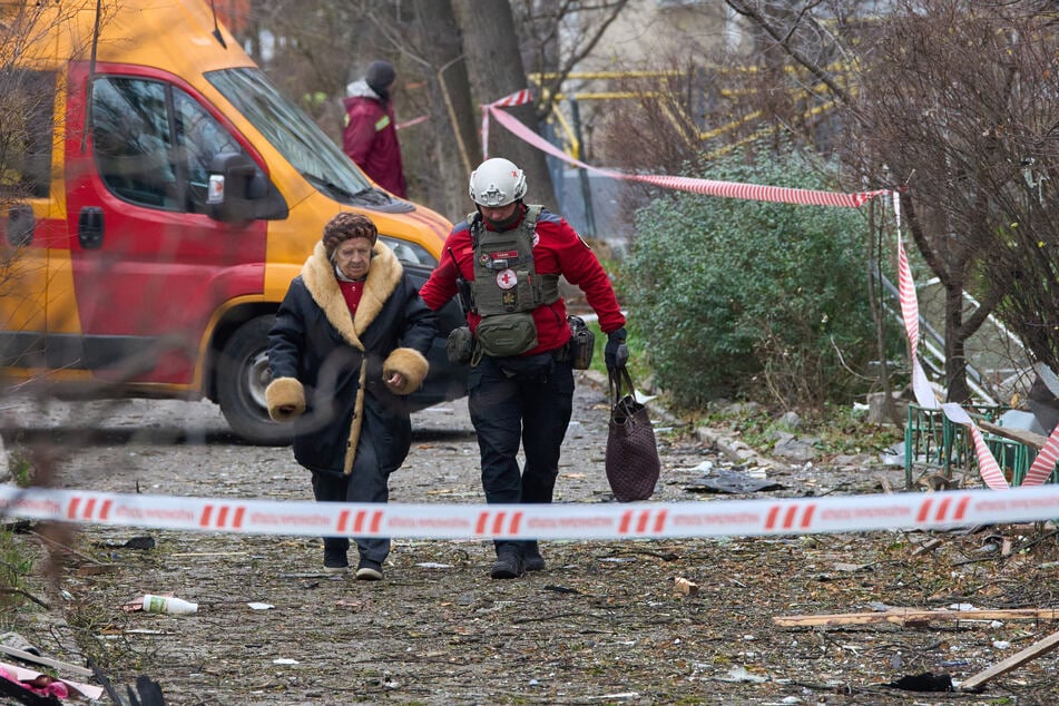 Ein Sanitäter evakuiert eine ältere Bewohnerin, nachdem eine russische Drohne ein Wohnhaus getroffen hat.