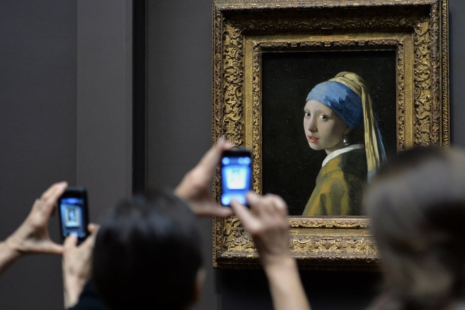 Visitors look at Johannes Vermeer's painting Girl with a Pearl Earring at the Frick Collection in New York, on October 21, 2013.