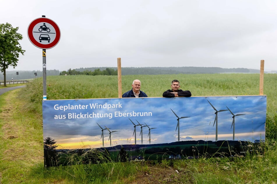 Chris Stegert und Max Einenkel an einem Plakat am Straßenrand. Die Bürgerinitiative hofft, die Windpark-Pläne durch Prostest stoppen zu können.