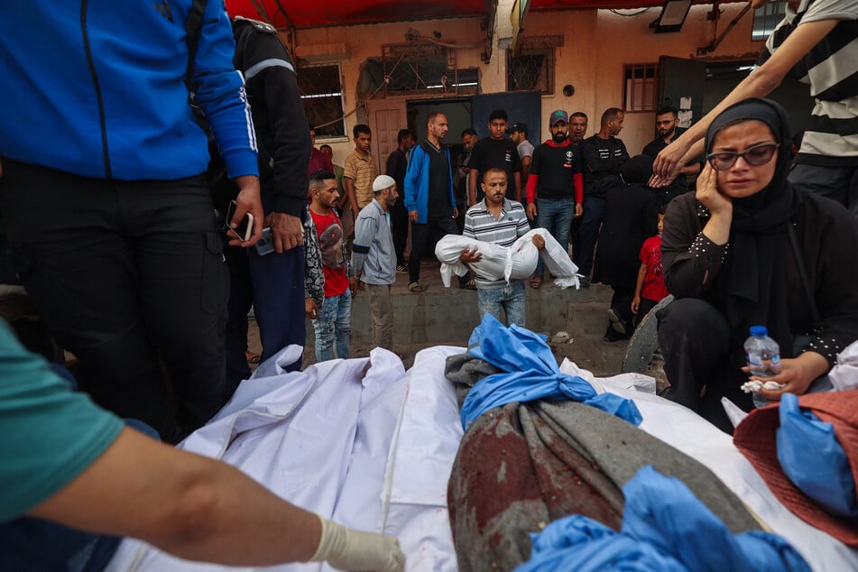 Palestinians mourn by the bodies of relatives who were killed in Israeli strikes at the Al-Aqsa Martyrs hospital in Deir el-Balah in the central Gaza Strip on May 18, 2025.