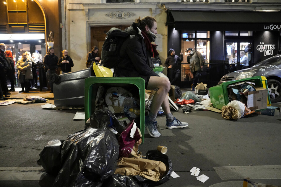 Ein Demonstrant sitzt auf einem umgestürzten Mülleimer während eines Protestes in Paris.