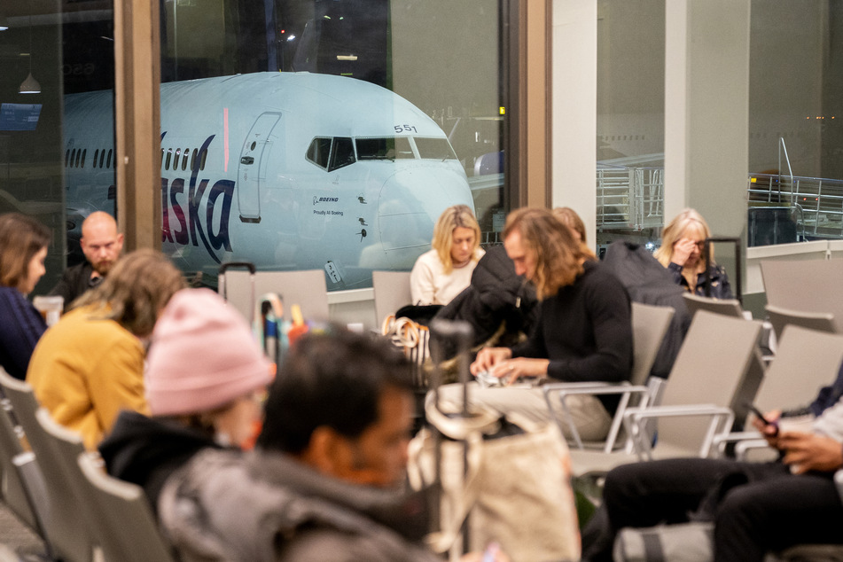 Travelers wait at a gate at Los Angeles International Airport on January 11, 2023, after the US Federal Aviation Administration ordered a temporary halt to all domestic flight departures.