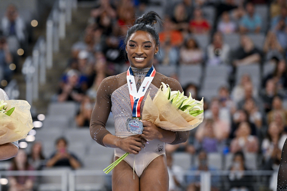 Simone Biles poses for a photo with her gold medal and commemorative belt buckle after finishing in first in the 2024 US Gymnastics Championships.
