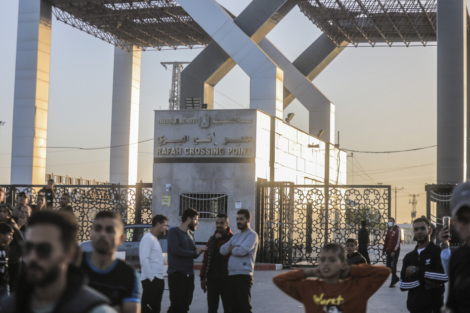 Palästinenser versammeln sich vor dem Tor des Grenzübergangs Rafah, um auf die Durchfahrt von Fahrzeugen zu warten, die israelische Geiseln aus dem Gazastreifen nach Ägypten transportieren.