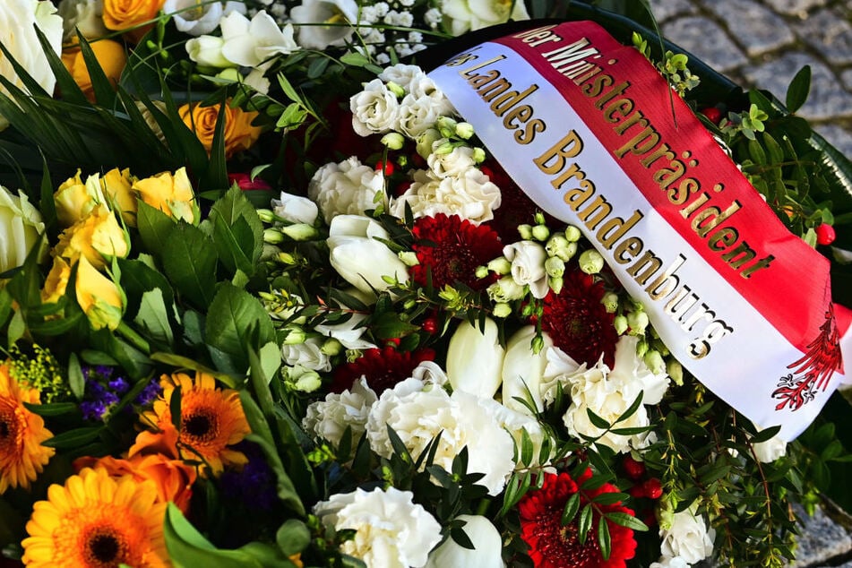 Blumen mit einer Schleife "Der Ministerpräsident des Landes Brandenburg" liegen neben anderen Blumen vor dem Eingang zur Einrichtung des diakonischen Anbieters Oberlinhaus. Die Brandenburger Landesregierung sieht nach dem gewaltsamen Tod von vier Heim-Bewohnern in Potsdam bisher keinen Zusammenhang mit der Arbeitssituation.