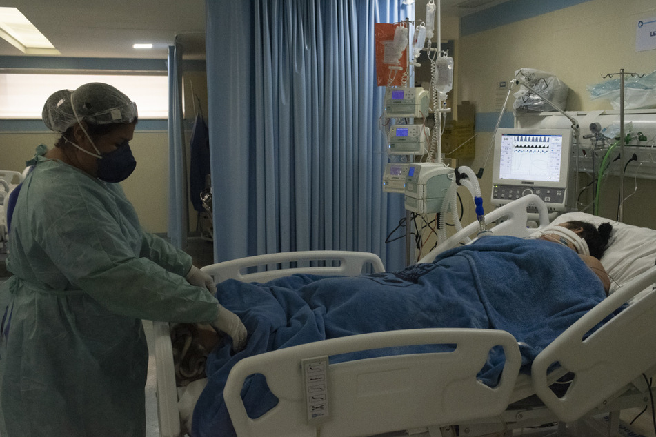 Eine medizinische Mitarbeiterin untersucht eine Patientin, die mit dem neuartigen Coronavirus infiziert ist, während sie auf der Intensivstation eines Krankenhauses in Rio de Janeiro an ein Beatmungsgerät angeschlossen bleibt.
