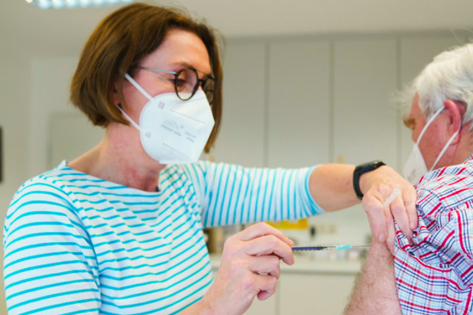 Eine Hausärztin verabreicht einem Patienten die Impfung gegen Covid-19. Rund 8500 Praxen in Bayern sollen am Mittwoch mit dem Impfen beginnen.