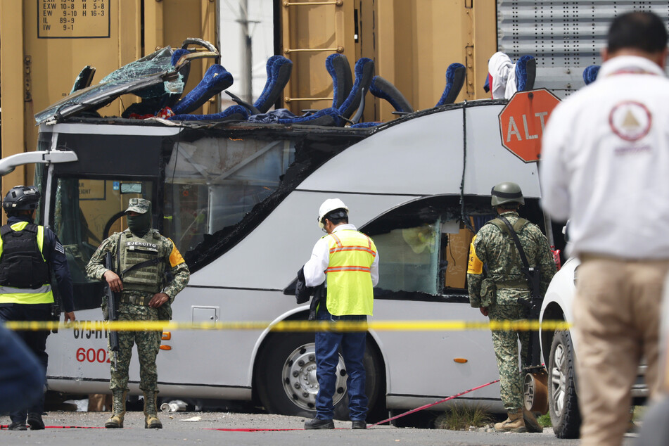Soldaten und Rettungskräfte arbeiten an der Stelle eines tödlichen Unfalls, bei dem ein Güterzug mit einem doppelstöckigen Bus zusammengestoßen ist.