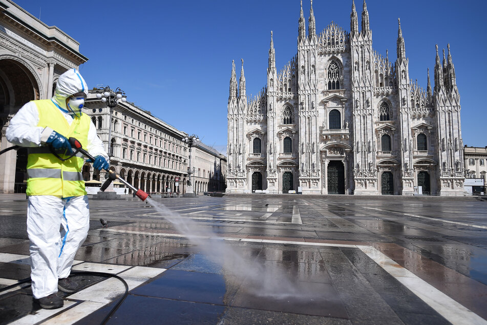 Ein Arbeiter in Schutzanzug reinigt den Boden auf der Piazza del Duomo in Mailand.