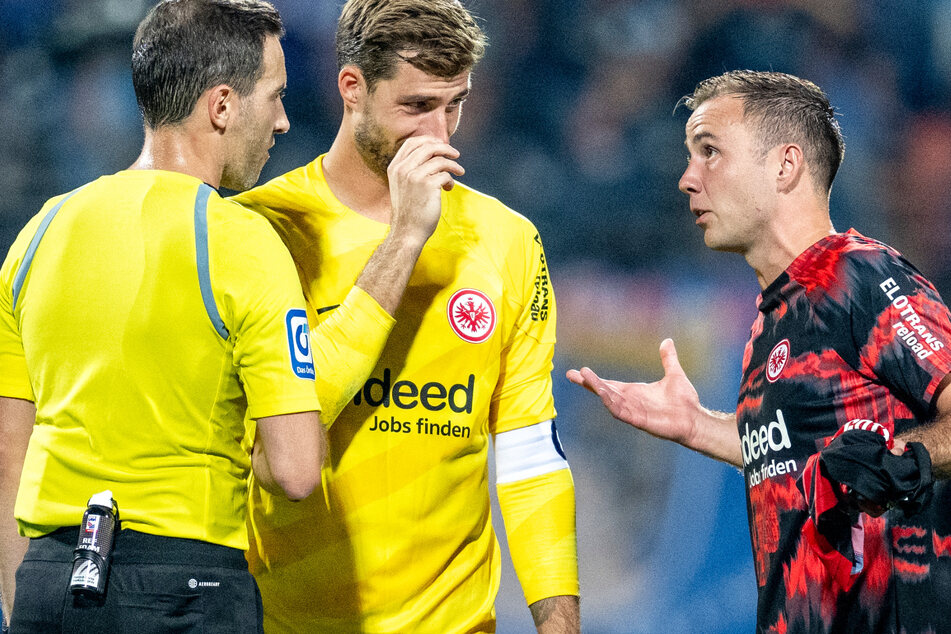 Schiedsrichter Benjamin Brand (34, l-r), Frankfurts Torwart Kevin Trapp (33) und Mario Götze (31) von Eintracht Frankfurt diskutierten nach dem Schlusspfiff wegen Brands Elfmeter-Entscheidung.