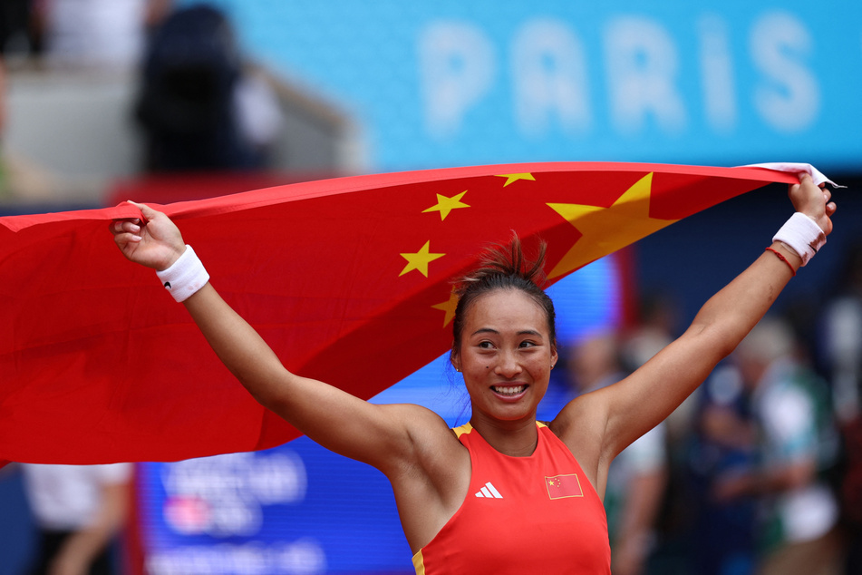 Zheng Qinwen raises her flag at the Paris Olympics after becoming China's first tennis singles gold medalist.