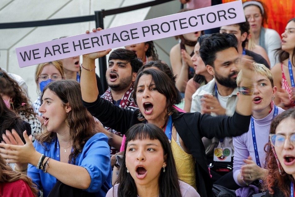 An activist raises a sign reading "We Are Heritage Protectors" during a protest against fossil fuels during the United Nations Climate Change Conference (COP28) in Dubai on December 12, 2023.