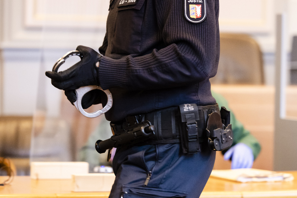 Ein Justizbeamter steht mit Handschellen im Kieler Landgericht. Dort beginnt der Prozess gegen einen 49-Jährigen. (Archivbild)