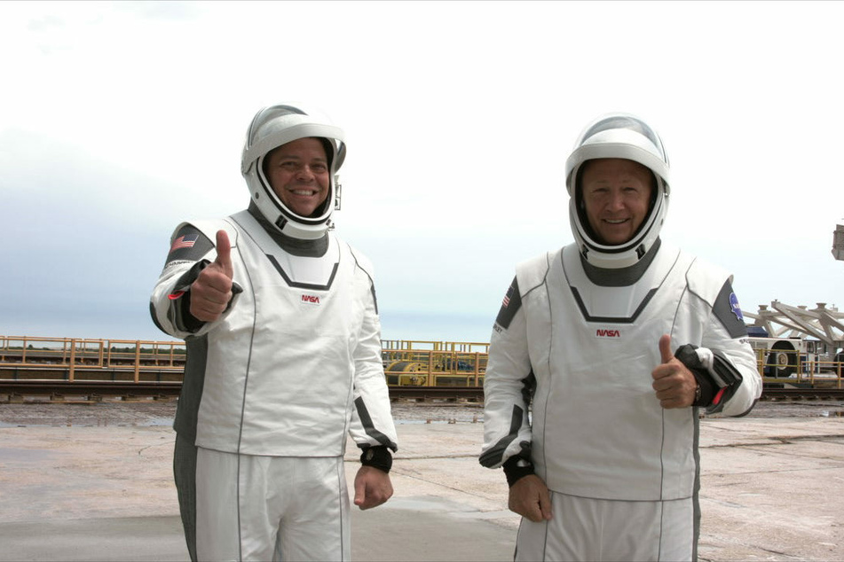 Die NASA-Astronauten Robert Behnken (l.) und Douglas Hurley gestikulieren vor dem Einstieg in die Besatzungskapsel "Crew Dragon" der "Falcon 9"-Rakete von SpaceX im Kennedy Space Center in Cape Canaveral.