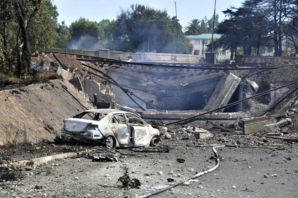 Ein ausgebranntes Fahrzeug markiert die Stelle, an der ein Tankwagen unter einer Brücke in Boksburg explodiert ist.