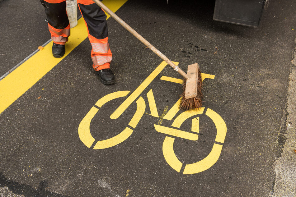 Ein Mitarbeiter einer Straßenunterhaltungsfirma fegt im Stadtteil Rothenbaum über ein Fahrradsymbol auf einer Pop-Up-Bikelane.