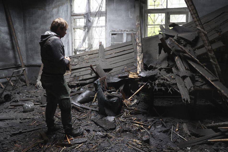 Eine Frau steht in der Region Donezk inmitten der Trümmer eines durch Granatenbeschuss zerstörten Hauses.