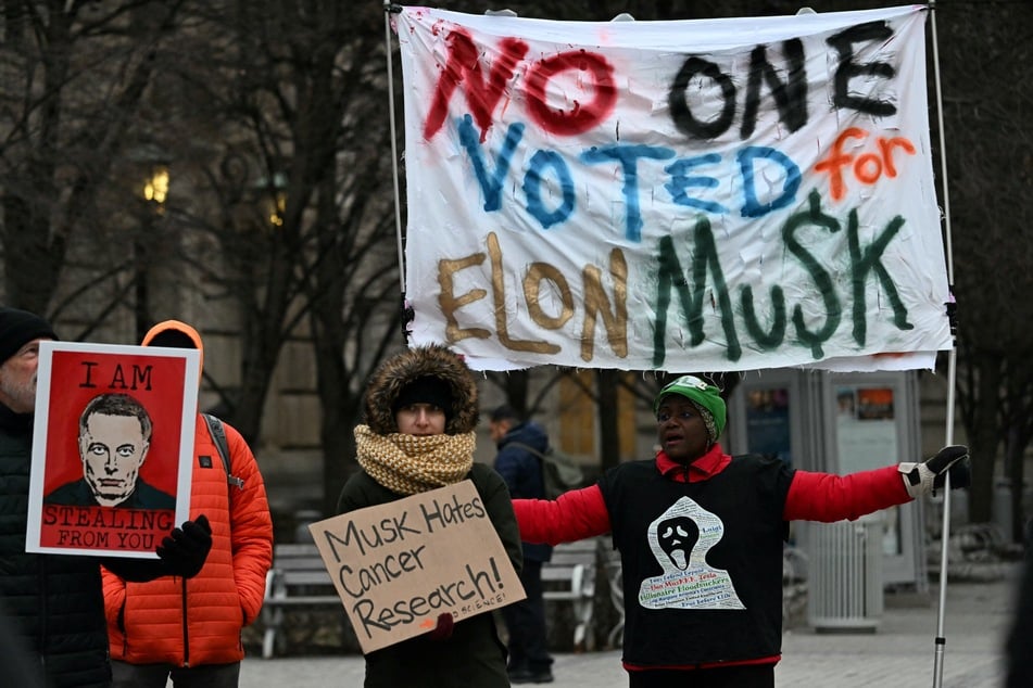 Protestors hold placards during a demonstration against the policies of US President Donald Trump and Elon Musk's Department of Government Efficiency (DOGE) near Musk's SpaceX headquarters in Washington, DC, on Wednesday.