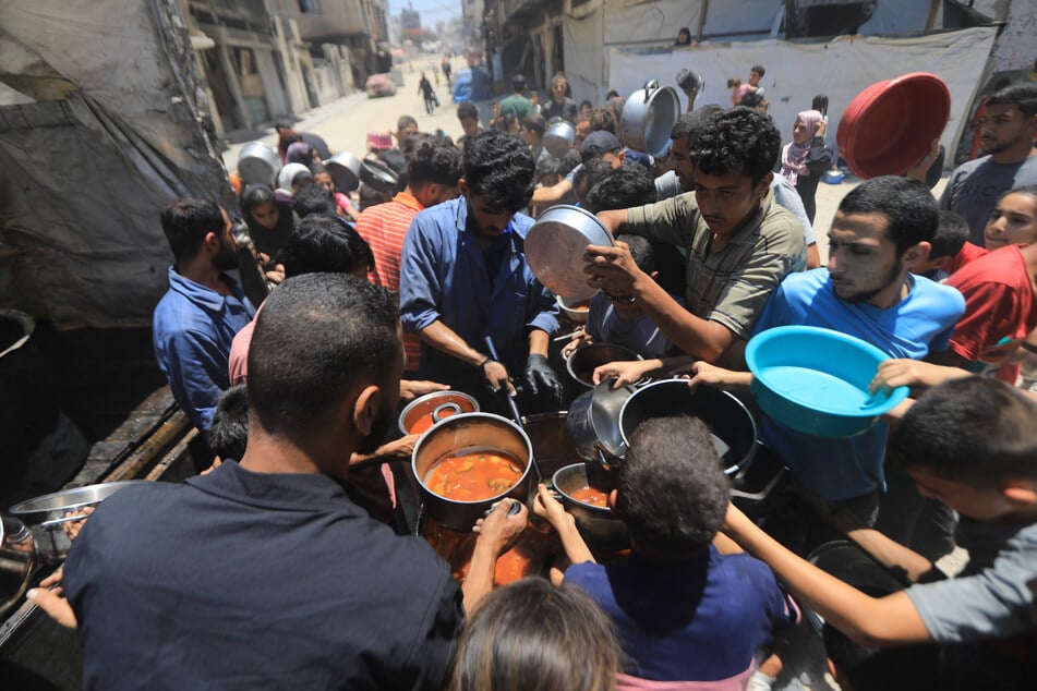 Palästinenser warten in langen Schlangen mit Töpfe auf die Ausgabe von Essen, die von Wohltätigkeitsorganisationen in Gaza-Stadt verteilt werden. (Archivbild)