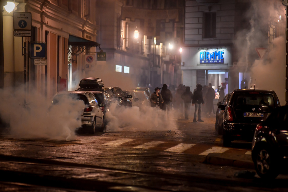 Eine Straße ist in Rauch gehüllt bei Ausschreitungen und Zusammenstößen zwischen Demonstranten und Polizei am Montagabend in der Innenstadt nach Protesten gegen die Regierungsmaßnahmen zur Eindämmung der Corona-Pandemie in Italien.