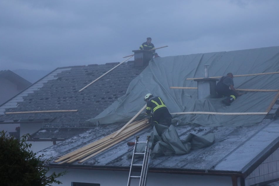 Feuerwehrleute arbeiten auf einem beschädigten Dach.
