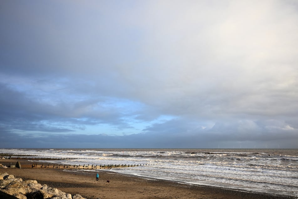 Am Tag nach dem Unglück ist ein Spaziergänger mit einem Hund am Strand von Withernsea unterwegs. Wenige Kilometer entfernt brennt der Öltanker.