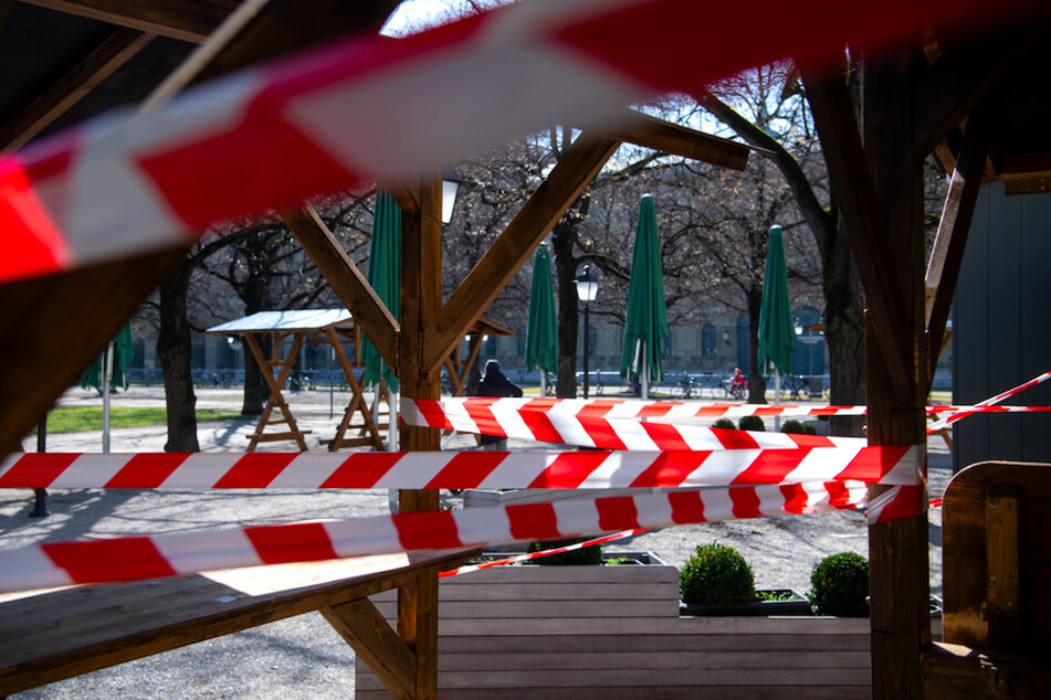 Tische und Stühle von einem geschlossenen Restaurant sind im Münchner Hofgarten mit Flatterband abgesperrt.