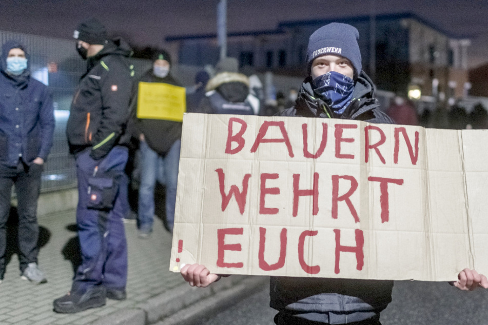 Ein Demonstrant trägt vor der Meierei Barmstedt ein Schild mit der Aufschrift "Bauern wehrt Euch".